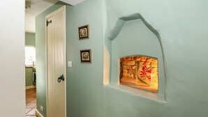 A hallway with a white door, a stone wall with a fireplace, and two framed pictures on the wall. - Bumble Bee (Oakham)