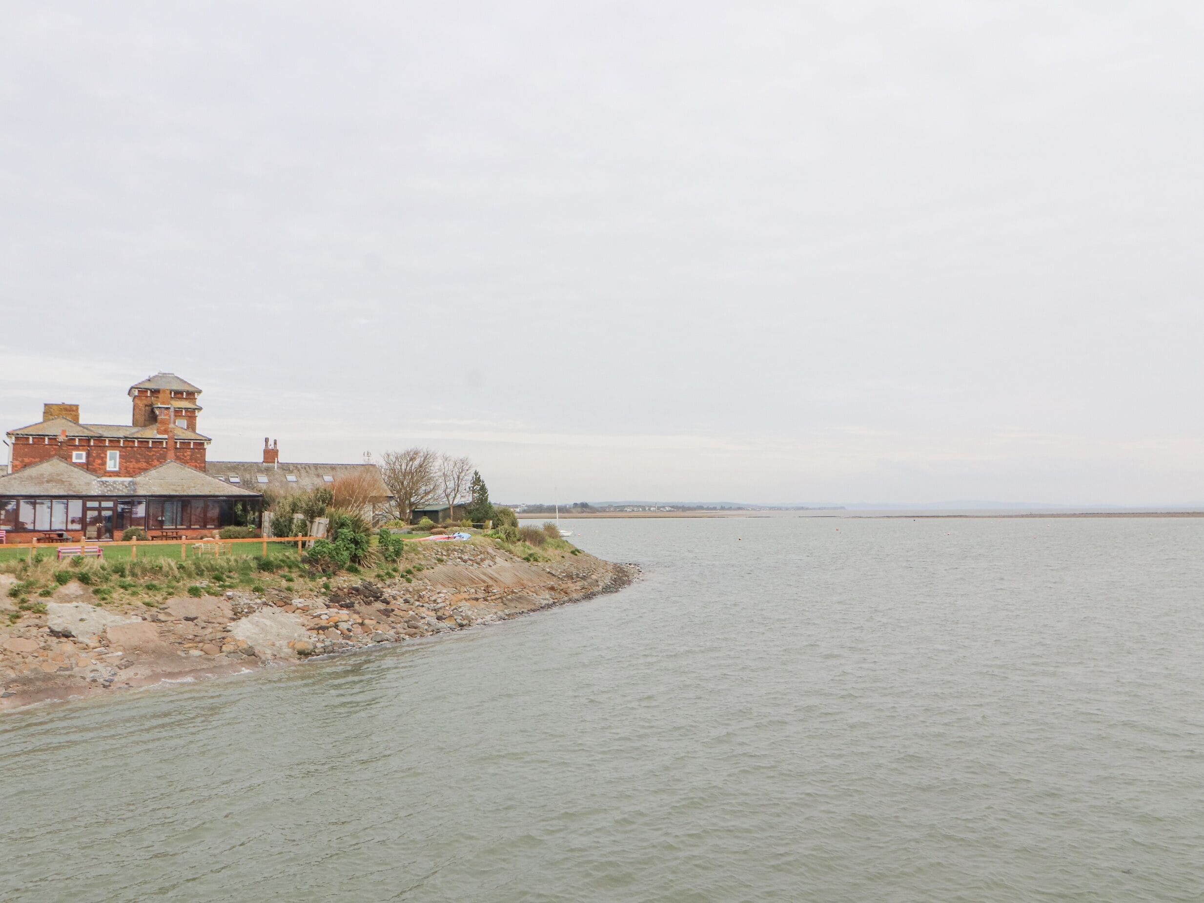 A riverside building with a tower, a covered seating area, and a view of the water.