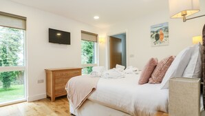 Quarto com cama, cómoda de madeira e televisão na parede.