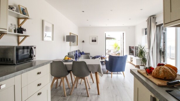A modern kitchen with a dining area, wooden cabinets, and a view to the outside. - Meadow View Barn (Wareham)