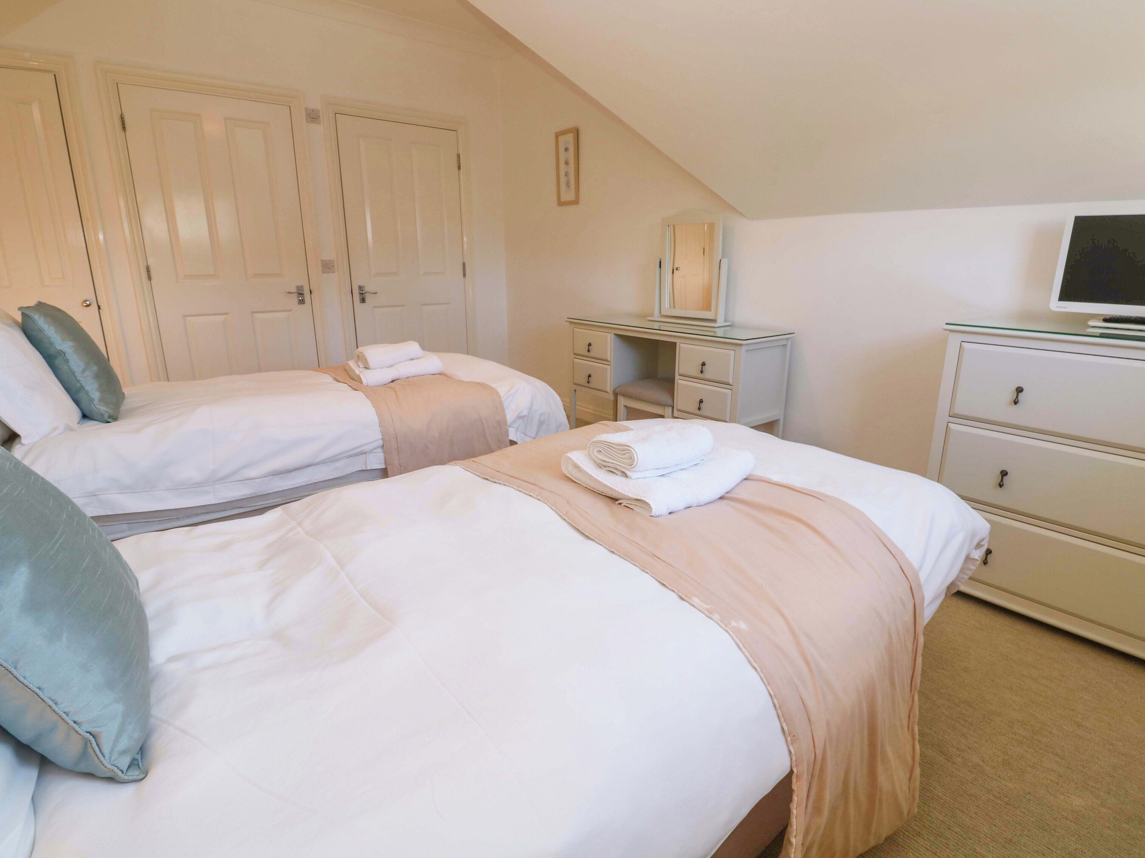 Une chambre d’hôtel avec deux lits, un bureau, une commode et un téléviseur.