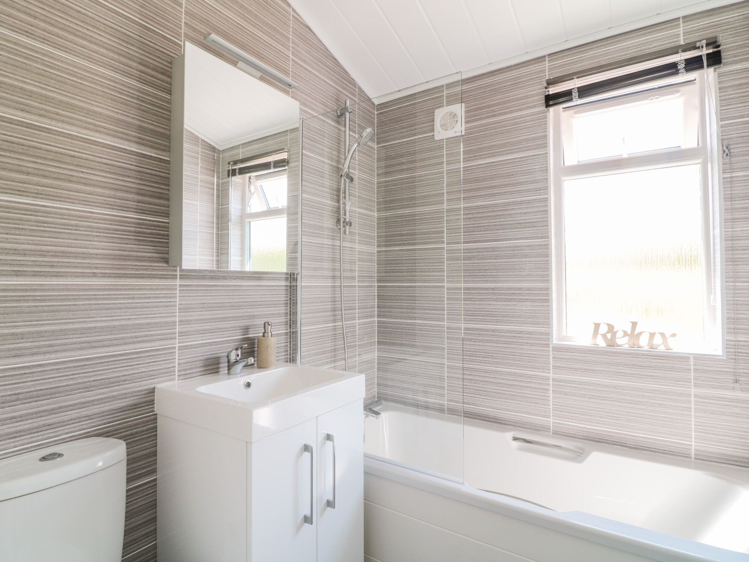 A modern bathroom with a white sink, vanity, and bathtub.