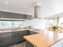 Una cocina moderna con una isla central, armarios grises y un amplio ventanal que proporciona luz natural.