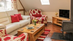 A cozy living room with a sofa, armchair, wooden coffee table, and a television.