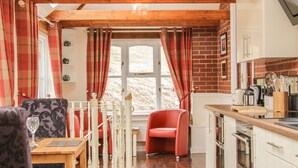 A cozy kitchen with a wooden ceiling, a dining area with a table and chairs, and a red chair.