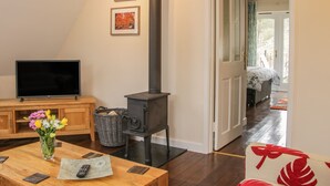 A cozy room with a wooden table, a TV, a fireplace, and a bed in the background.