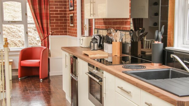 A modern kitchen with white cabinets, a wooden countertop, and stainless steel appliances.