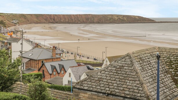 A coastal town with a beach, houses with traditional architecture, and a clear view of the sea. - The Garden Apartment (Filey)