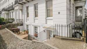 A white building with a balcony, a stone wall, and a gravel pathway. - The Garden Apartment (Filey)