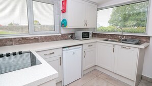 Een moderne keuken met witte kasten, een ingebouwde magnetron, een vaatwasser en een gasfornuis.