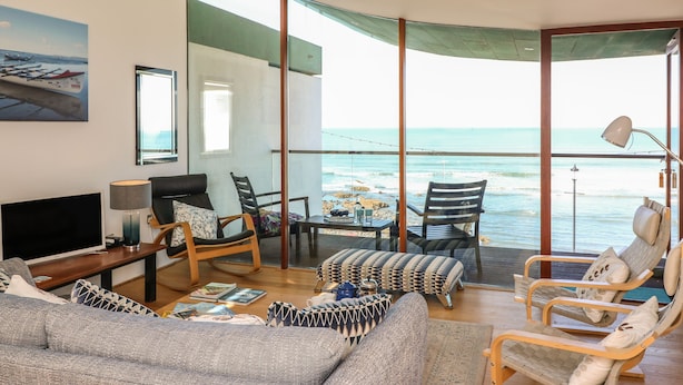 A spacious living room with a large window overlooking the ocean, furnished with a sofa, chairs, and a coffee table. - The Lookout (Bideford)