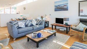 A modern living room with a grey sofa, a wooden coffee table, a TV, and a rocking chair. - The Lookout (Bideford)