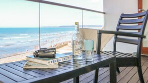 A balcony with a view of the beach, a bottle of liquor, a glass of water, and a book. - The Lookout (Bideford)