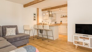 Una sala de estar moderna con un sofá gris, una mesa de centro y un mueble para TV.