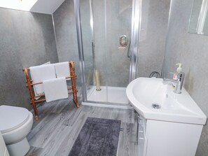 A modern bathroom with a glass shower enclosure, a white sink, and a toilet.