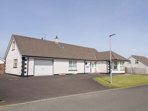 A residential building with a tiled roof, a garage, and a small front yard.