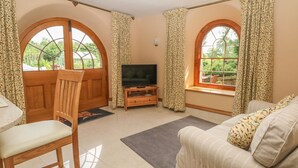 Un salon avec un téléviseur, des meubles en bois et de grandes fenêtres.