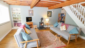 A cozy living room with a fireplace, wooden furniture, and a staircase. - Bamforth Cottage (Holmfirth)