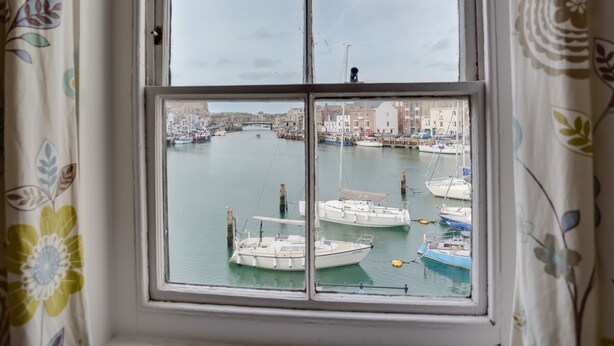 Ein Fenster mit Blick auf eine Marina voller Boote, eine Brücke und Gebäude im Hintergrund.