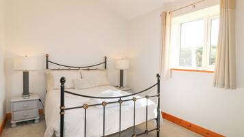 A neatly arranged bedroom with a bed, bedside tables, and a window with curtains.