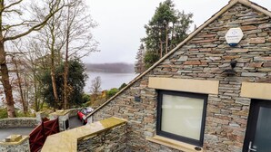 A stone building with a large window and a hot tub on the patio. - Lake View (Windermere)