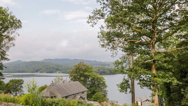 A stone wall, a stone building, and a large tree. - Lake View (Windermere)