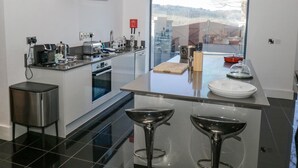 Cozinha moderna com uma ilha grande, eletrodomésticos de aço inoxidável e vista para o exterior.
