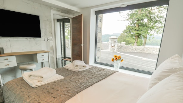 Quarto de hotel moderno com uma cama grande, uma escrivaninha e um banheiro.