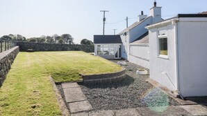 A white house with a small garden and a paved area. - Buarthau Cottage (Caernarfon)