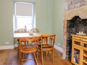 A dining area with a wooden table and chairs, a window with a view, and a stone fireplace.