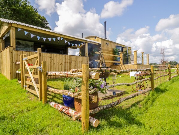 A rustic wooden cabin with a metal roof, a wooden fence, and a solar panel. - High Rigg Shepherd's Retreat (Brampton)