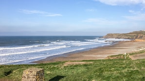 Eine Küstenlandschaft mit Strand, Wiesen und Klippen.