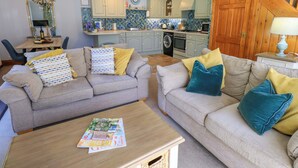 A living room with two sofas, a coffee table, and a dining area with a table and chairs. - Waterhead Cottage (Windermere)