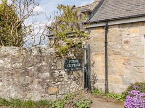 A stone cottage with a sign reading "Forge Cottage Self Catering Cottage." - Forge Cottage (Morpeth)