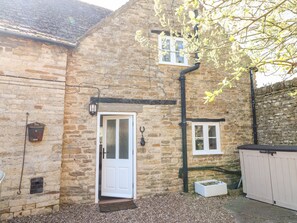 A stone building with a white door, a small window, and a wall-mounted light fixture. - Manor View (Oakham)
