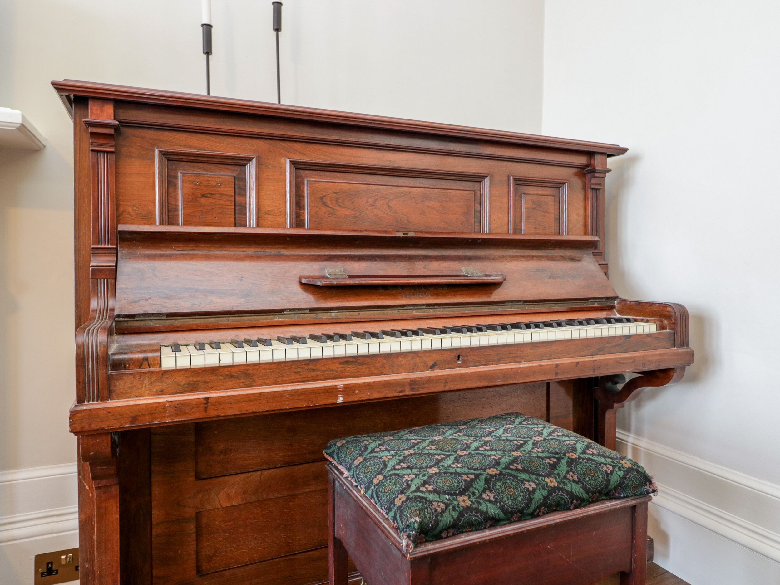 A wooden upright piano with a bench in front.