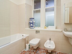 A bathroom with a bathtub, toilet, bidet, and a window with a vase on the windowsill. - East Firwood (Rothesay)