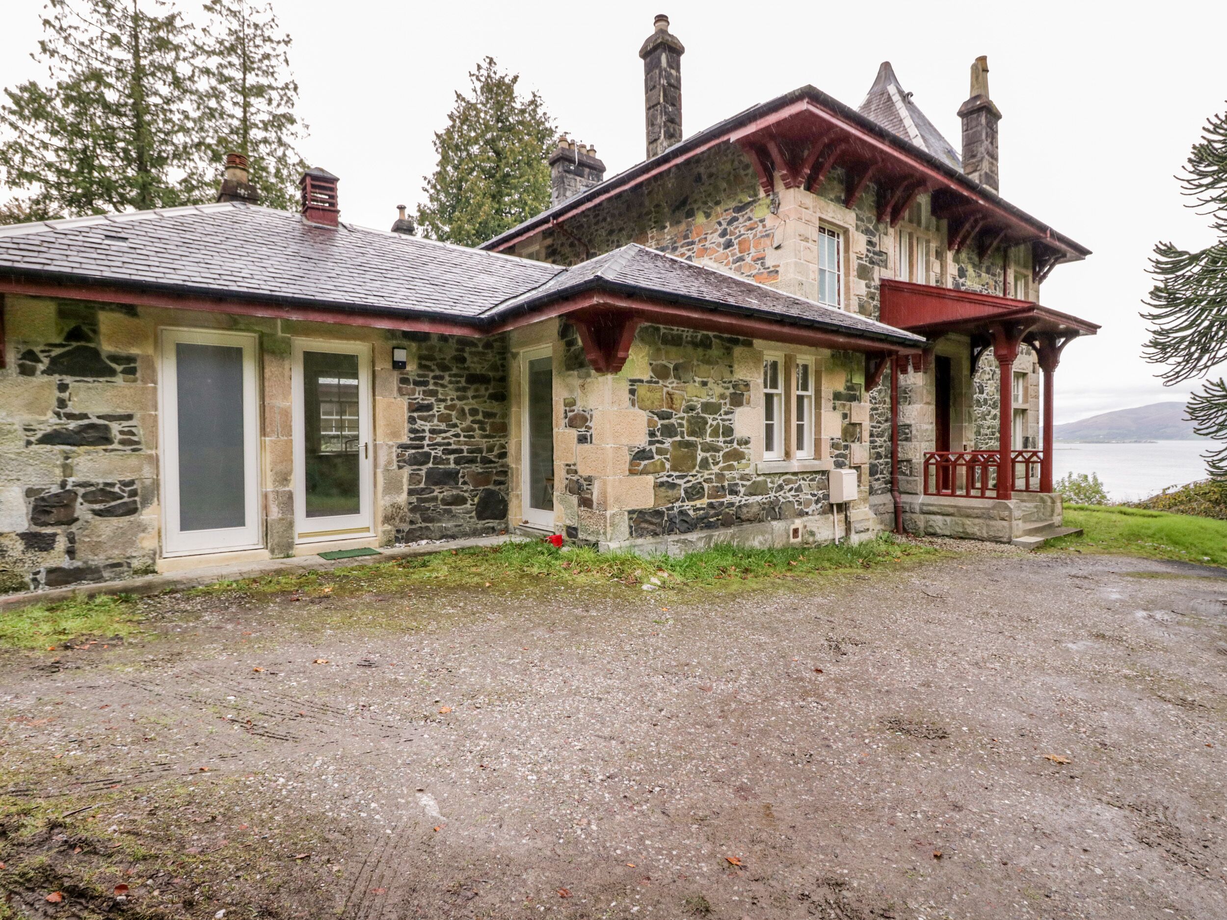 A stone building with a red porch and a view of the water.