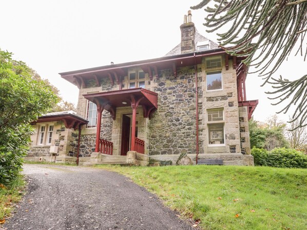 A stone building with a red porch and a gravel driveway. - East Firwood (Rothesay)