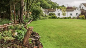 A residential area with a well-maintained lawn, a wooden fence, and houses with white exteriors and brown roofs. - Quiet Waters Cottage (Coleraine)