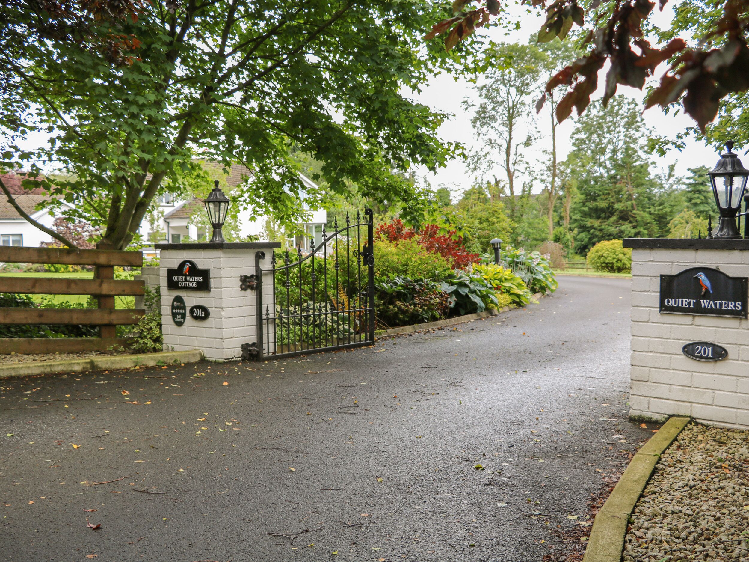 A gated entrance with a sign reading "Quiet Waters Cottage."
