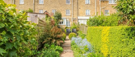 A row of terraced houses with a garden pathway leading to the front door.