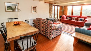 Una sala de estar acogedora con una mesa de comedor de madera, un sofá estampado y un sofá rojo.
