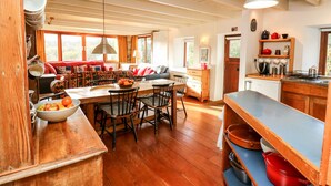 Una cocina amplia con pisos de madera, un comedor con mesa y sillas, y una encimera con diversos utensilios.