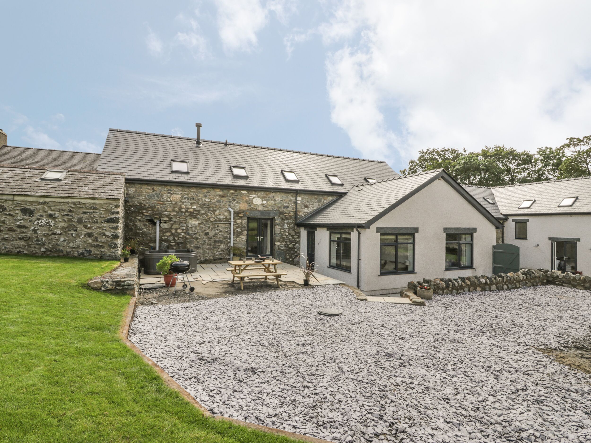 A stone building with a gravel driveway and a grassy lawn.