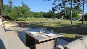 Un patio al aire libre con una mesa lista para comer, rodeado de muebles de mimbre y plantas en macetas.