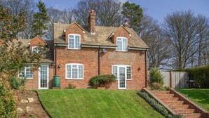 A two-story brick house with a well-maintained lawn and a brick staircase leading to the front door. - Knights Cottage (Maidstone)