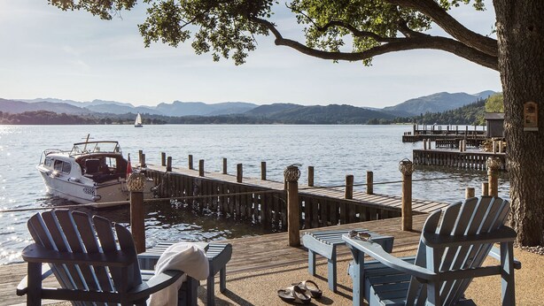 A lakeside dock with wooden chairs and a boat. - Lakeside Cottage (Windermere)