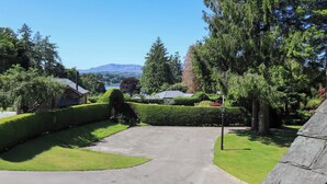 A residential driveway leading to a house with a well-maintained lawn and a large tree. - Lakeside Cottage (Windermere)