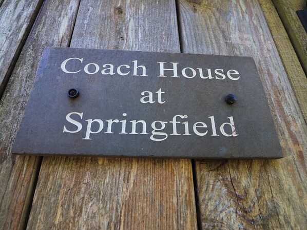 A sign with the text 'Coach House at Springfield' on a wooden surface.